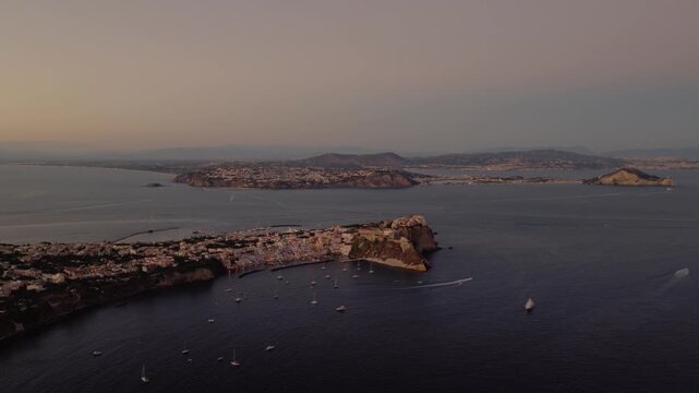 Boats Floating In The Sea By Procida Island At Dusk In Phlegraean Islands, Naples, Southern Italy. - aerial shot
