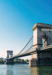 Obraz premium Impressive historical suspension crossing structure supported by huge stone towers and long, heavy metal chains spanning a large waterway, column, arch, walkway