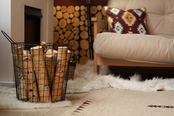Naklejka premium Basket of firewood with sofa near fireplace in living room, closeup