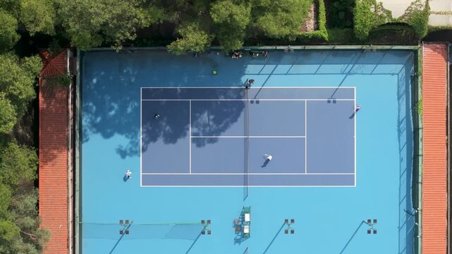 Aerial view drone shot, rising above people playing tennis in the morning