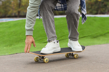 Legs of young man with skateboard in park, closeup © Pixel-Shot