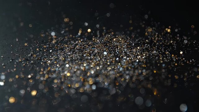 Dark, textured surface with glittery specks, a bokeh effect, and scattered, luminous dots
