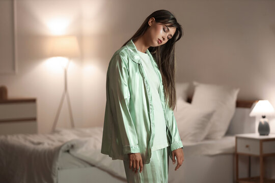Female sleepwalker near bed in evening at home