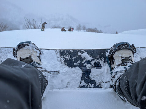 Snowboard boots strapped into bindings covered in fresh snow on a mountain