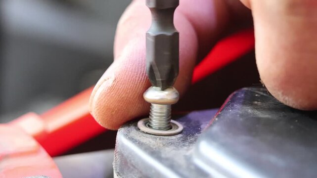Detailed automotive maintenance showing jumper cable connection to car battery terminal for emergency jump start power, plus precision screwdriver repair for vehicle systems