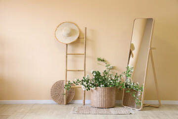 Floor mirror, stepladder and wicker basket with blooming jasmine flowers in interior of room