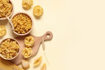Fotobehang Eten Composition with bowls of different types of raw pasta and wooden cutting board on beige background  © Pixel-Shot