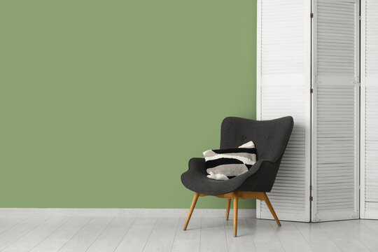 Folding screen and chair near green wall in room