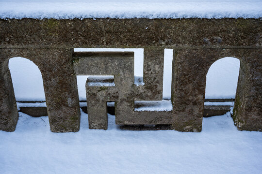 Buddhist Swastika Symbol Carved in Traditional Stone Wall with Winter Snow