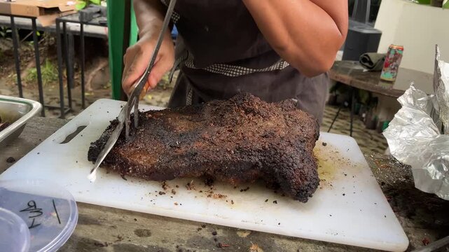 Man slicing a loaf of smoked brisket pastrami on a cutting board, with fun vibes