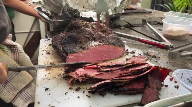 Man slicing a loaf of smoked brisket pastrami on a cutting board, with fun vibes