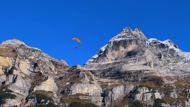 Hang Glider base jumper landing parachute Murren M&uuml;rren Gimmelwald Swiss Alps chalet Lauterbrunnen Valley sunny autumn fall blue sky Switzerland Schweiz grass Jungfrau Allemdhubel mountain cliff slabs