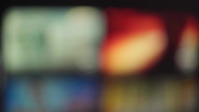 Abstract blurred television screen with colorful streaming content in a dark room, home entertainment and binge watching concept