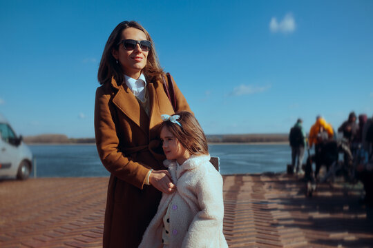 Mother and Daughter Waiting Together for the Holiday Ferry Trip. Woman and her little girl patiently bide their time at the coastal pier before their seasonal getaway 