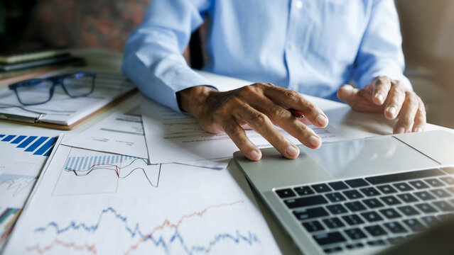 close up shot, asian businessman using laptop with financial report and chart meeting online discussing investment plan  in office