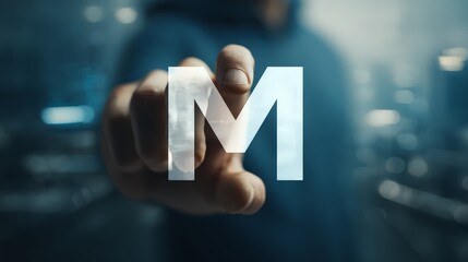 A close-up, first-person perspective of a man's hand interacting with a large, glowing, translucent letter "M".