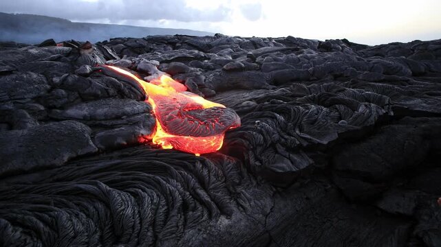 Melting hot red lava flows on black ground in Hawaii Big Island at sunset time