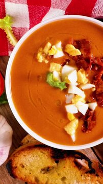 Spanish salmorejo cream with ham and egg on wooden table