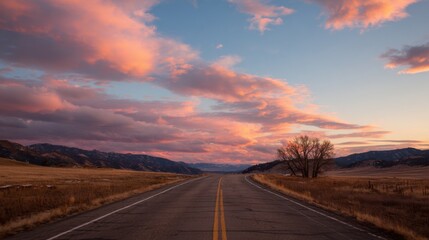 Stunning sunset over open road with dramatic clouds in mountainous landscape.