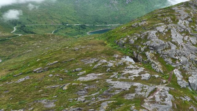 Aerial, forward drone flight above Norwegian mountains, trail to Barden mountain. Hikers with two dogs walking on path. Senja island in Norway. Beautiful landscape, wild nature. Arctic outdoor travel 