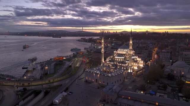 Aerial drone view of Istanbul historic Golden Horn, showing the Eminonu New Mosque or Yeni Cami, Galata Bridge, and Bosphorus at sunrise or sunset. Topkapi Palace and Hagia Sophia in the distance.