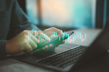 Man Using Smartphone and Laptop with Stock Market Candlestick Graph Overlay