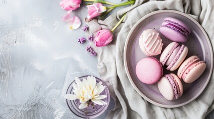 Colorful Macarons with Pink Tulips and White Flower on Light Textured Surface