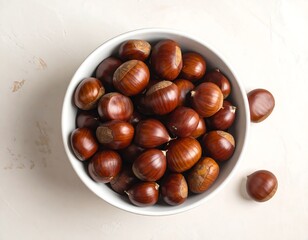 Obraz premium Overhead shot of chestnuts in a white bowl on a textured surface