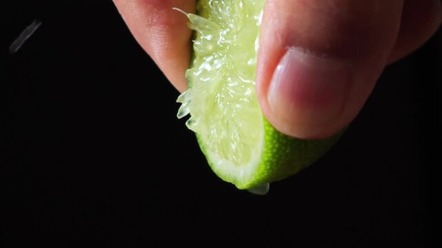 Close-up of hands squeeze juice from lemon on black board