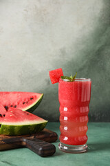 Naklejka premium Glass of tasty watermelon juice with mint on green table