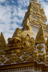 Fototapeta premium Phra That Phanom, iconic Buddhist stupa with golden carvings and white architecture, rising against a bright blue sky. Sacred Thai temple landmark, rich cultural heritage and spiritual atmosphere