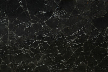 a black glass screen that is cracked and shattered into pieces on a dark background