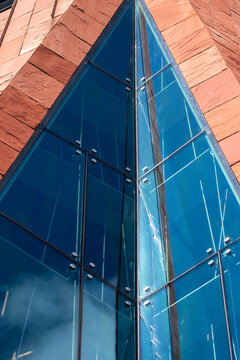 Modern glass pyramid building facade with blue reflection creating abstract geometry for contemporary architecture background and design concept