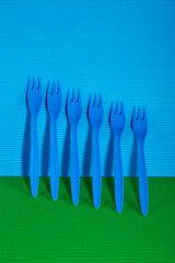 Blue plastic forks on a colored background