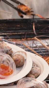 grilled river prawn on the grill. thai chef is turning the prown on the grill in the background. slow motion