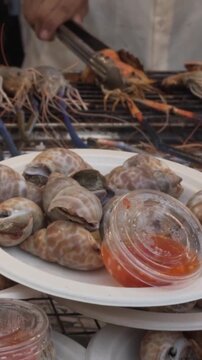 grilled river prawn on the grill. thai chef is turning the prown on the grill in the background. slow motion