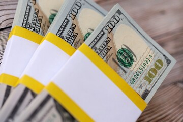 Three packs of ten thousand US dollar bills on wooden background. Packs of hundred dollar bills in stack on brown wood planks close up © mehaniq41