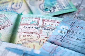 Fototapeta premium Big amount of passport pages full of colorful stamps after travel and border crossing. Tourism and border control concept. Immigration and travel around the world