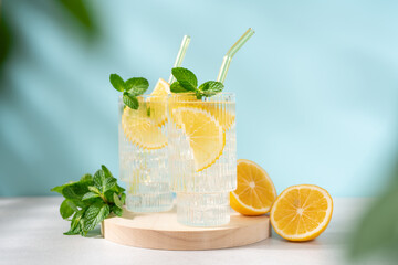 Fototapeta premium Fresh Lemonade in Tall Glass with Lemon Slice and Mint on Blue Background, Refreshing Summer Drink with Copy Space, Clean Minimal Beverage Concept