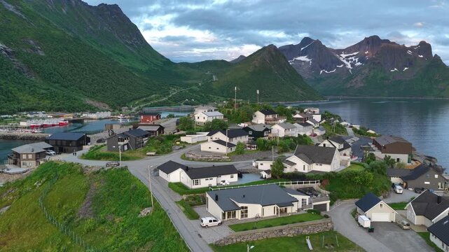 Aerial, forward drone flight, slow turn, above Hus&oslash;y island and village Amazing wild nature during midnight sun in summer on Senja island in Norway. Beautiful landscape, wild nature. Fjord, mountains.