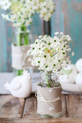 Florist at work: woman shows how to make Easter floral table decoration with arabian star flowers and gypsophila paniculata twigs in simple wooden box. Step by step, tutorial.