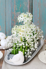 Florist at work: woman shows how to make Easter floral table decoration with arabian star flowers and gypsophila paniculata twigs in simple wooden box. Step by step, tutorial.