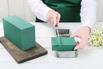 Florist at work: woman shows how to make Easter floral table decoration with arabian star flowers and gypsophila paniculata twigs in simple wooden box. Step by step, tutorial.