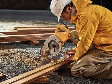 Man measuring decking board, circular saw