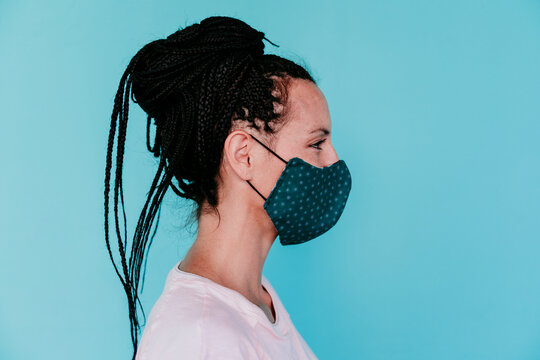 Woman wearing protective face mask with hair bun against turquoise background