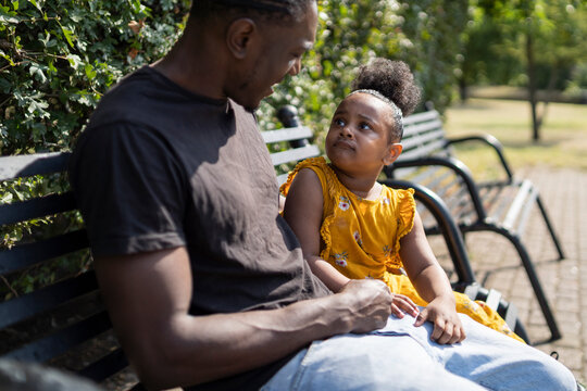 Father and daughter sitting on a bench in a park