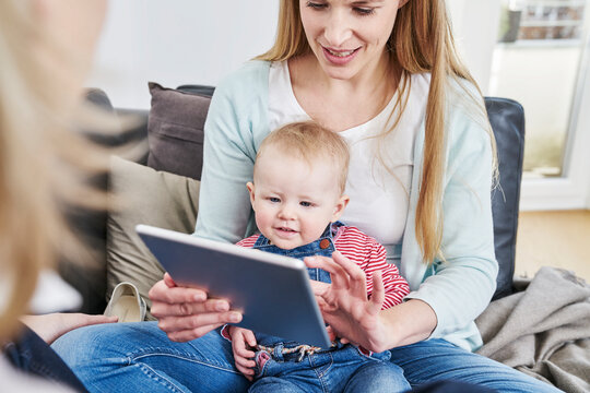 Mother and baby girl at home looking at tablet
