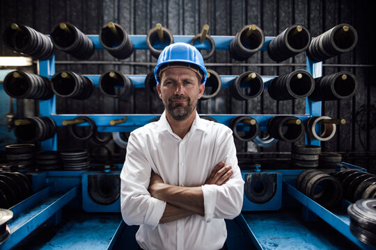 Male entrepreneur with arms crossed standing in steel mill