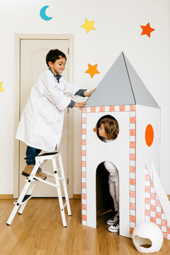 Siblings playing astronaut and researcher at rocket