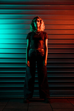 Stylish young woman at night in front of roller shutter
